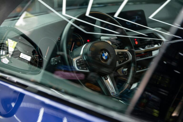Close-up view of a BMW's interior focusing on the steering wheel and dashboard.