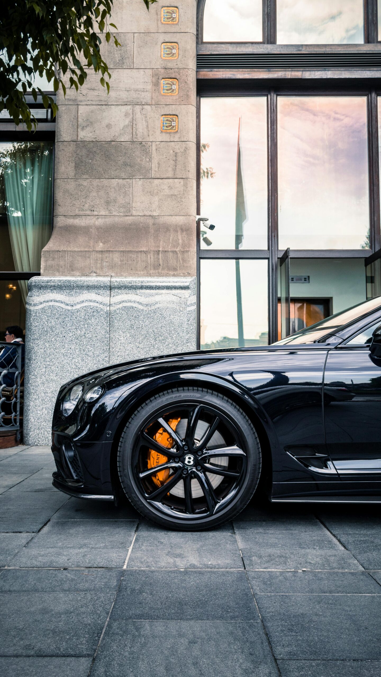 Elegant black Bentley parked in front of a modern building showcasing luxury.